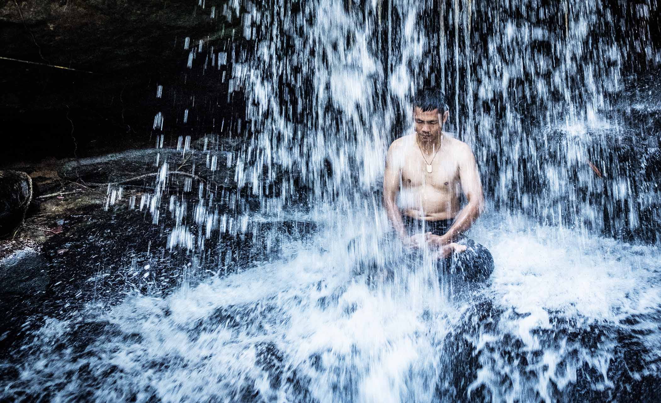 Man in a waterfall, rural Cambodia